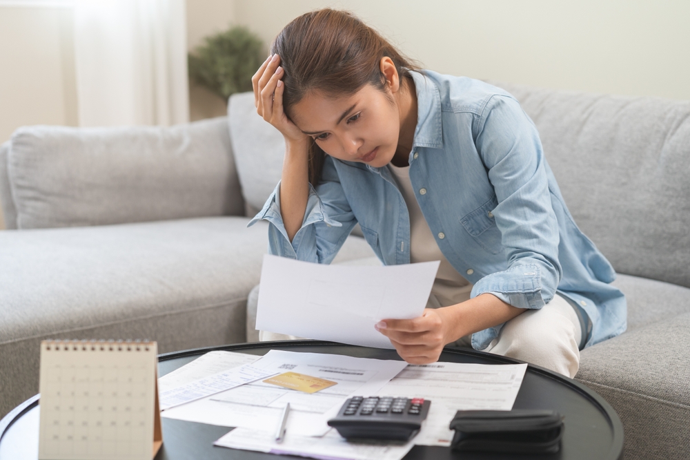 Stressed New Jersey worker reviewing overdue bills and paperwork while a workers’ comp claim is pending and income is delayed.